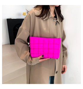 Detailansicht der gesteppten Clutch in fluoreszierendem Pink an Model im Trenchcoat
