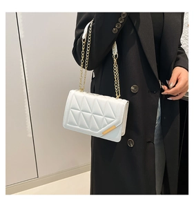 Close-up of a white quilted crossbody bag with a gold chain and minimalist metal detail