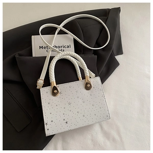 Detailed shot of star pattern handbag with braided handles on a black blazer