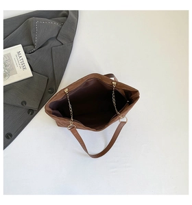 Dettaglio della borsa tote marrone con catena dorata e ampio scomparto interno