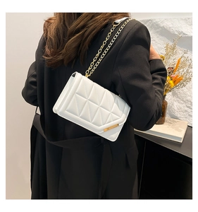 White quilted crossbody bag with gold chain strap shown on a model for casual style
