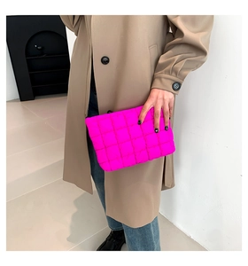 Detail der neongurken gesteppten Clutch-Tasche kombiniert mit einem klassischen Trenchcoat