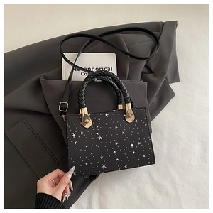 Detail of black star print handbag with woven leather handle and gold hardware