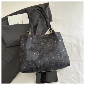 Detail of black tote bag with silver star and moon patterns and metal chain straps