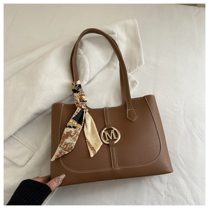 Brown leather tote bag featuring golden M-buckle and elegant patterned silk scarf handle
