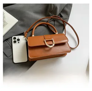 Brown leather handbag detail showing size comparison with a smartphone and gold hardware