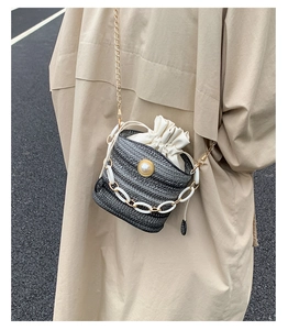 Detail of woven bucket bag featuring large pearl buckle and double chain strap