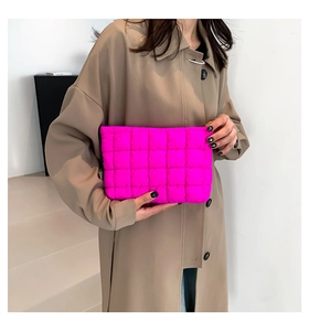 Detail einer gesteppten rosa Puff-Handtasche, gehalten von einer Frau im Trenchcoat
