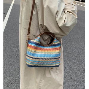 Rainbow striped woven crossbody bag with brown leather handles and adjustable shoulder strap