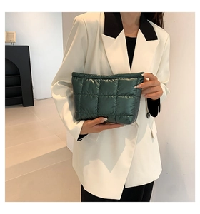 Détail d'une pochette matelassée vert foncé avec motif à carreaux tenue par un mannequin