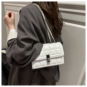 Detail of white quilted leather crossbody bag with silver chain strap and metal swivel lock