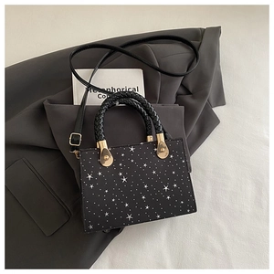 Detail of black crossbody bag featuring white star pattern and golden metal hardware