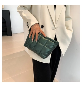 Détail d'une pochette matelassée vert foncé avec finition brillante et motifs carrés