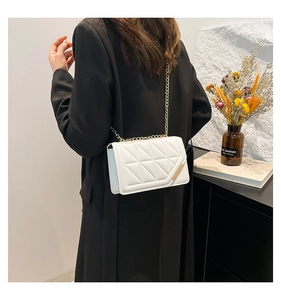 Modern white quilted shoulder bag with gold chain strap shown on model's shoulder