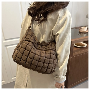Sac fourre-tout matelassé marron porté à l'épaule dans un style de vie chic