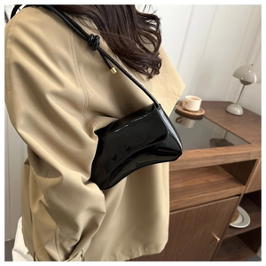 Detail einer schwarzen Lackleder-Halbmondtasche mit geknotetem Schultergurt-Design