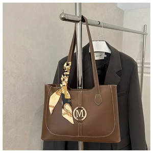 Detail of dark brown leather tote with contrast stitching and silk scarf accessory