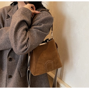 Brown suede bucket bag crossbody style on grey blazer for a chic commuting look