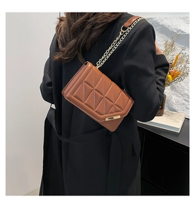 Close-up of brown quilted handbag featuring diamond stitching and gold chain strap detail