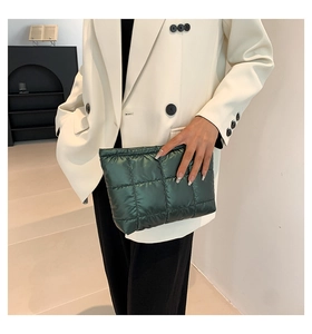 Gros plan d'une pochette matelassée vert foncé avec finition brillante et motif à carreaux