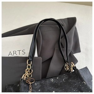 Detail of moon and star print tote bag with golden chain and leather shoulder strap