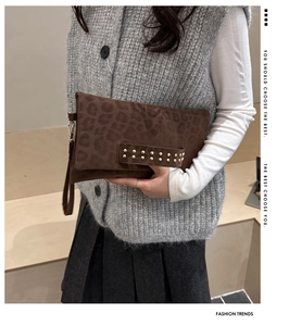 Dettaglio della pochette leopardata con borchie dorate e cinturino da polso elegante