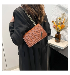Close-up of brown quilted leather bag featuring gold chain strap and side metal accent