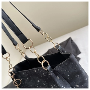 Detail of black tote bag featuring celestial star moon prints and gold chain strap