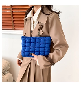 Detail einer hellblauen gesteppten Puffer-Clutch-Tasche, gehalten von einem Model
