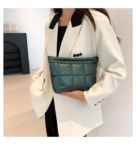 Gros plan d'un sac à main matelassé vert foncé avec une finition métallique brillante