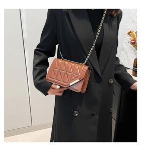 Close-up of brown quilted leather bag with gold chain strap worn by a model in a blazer