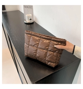 Détail d'une pochette en nylon matelassé marron avec finition brillante et fermeture
