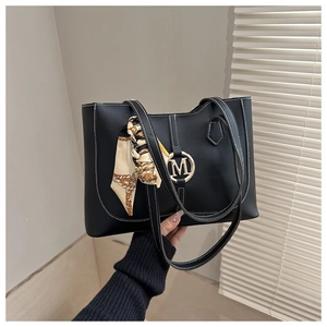Close-up of black leather tote with white stitching, gold M logo and decorative scarf