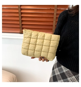 Nahaufnahme einer cremefarbenen Stepp-Clutch mit minimalistischem quadratischem Gittermuster