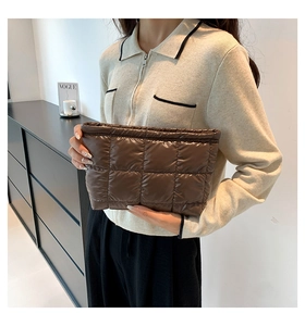 Pochette matelassée en nylon marron avec grandes surpiqûres carrées tenue par un mannequin
