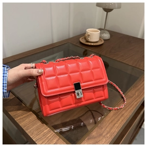 Elegant red quilted leather crossbody bag with silver chain strap on a wooden table