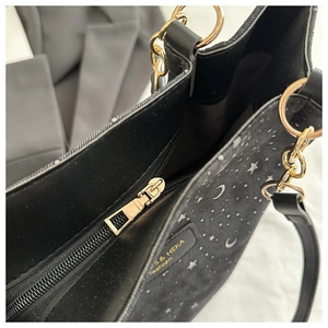Detail of black star and moon canvas tote bag with gold zipper and brand tag