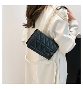 Detail of black quilted shoulder bag with gold chain strap and geometric texture
