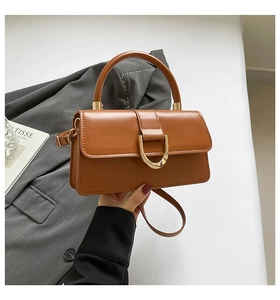 Close-up of brown faux leather handbag featuring a golden D-shaped metal buckle and handle