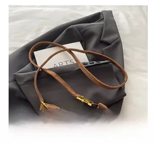 Detail of a thin brown suede strap with golden buckle on a vintage handbag texture