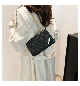 Detail of black quilted leather bag with geometric stitching and gold chain strap