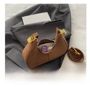 Interior view of brown suede crescent bag showing capacity for cosmetics and long strap