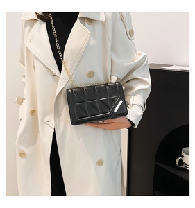 Close-up of black quilted shoulder bag with gold chain and silver metal accent