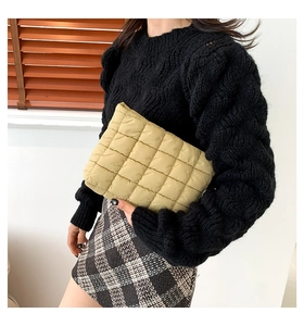 Detail der beigen gesteppten Clutch mit weicher Puffer-Textur in der Hand