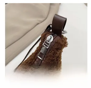 Detail von silbernem Reißverschluss und Ledergriff an brauner Plüschtasche