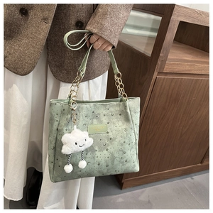 Detail of light green star cutout tote bag with a plush cloud charm and gold chain