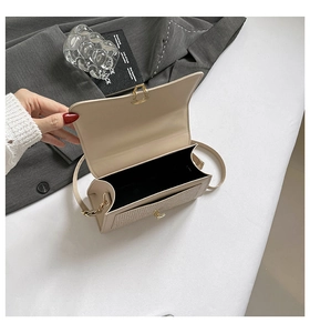 Dettaglio della borsa beige con texture intrecciata e chiusura a girello dorata