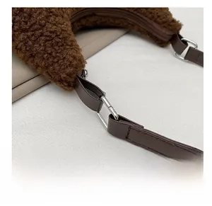 Detail der silbernen D-Ring-Schnalle und des Reißverschlusses an der braunen Plüschtasche
