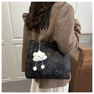 Star and moon print tote bag with plush cloud charm on a model in a brown blazer