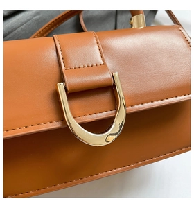 Detail of caramel brown leather handbag featuring a vintage gold D-ring buckle closure